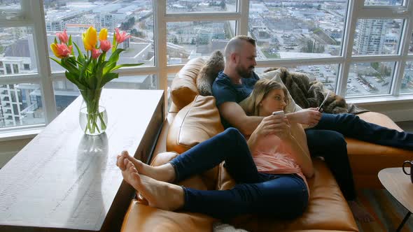 Couple using digital tablet and mobile phone in living room 4k