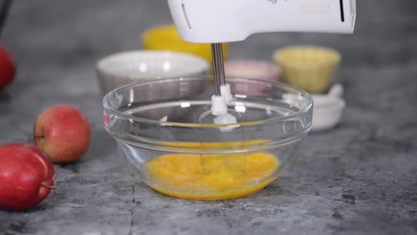 Chef's Hands Beat Raw Eggs and Sugar in a Glass Bowl with a Mixer