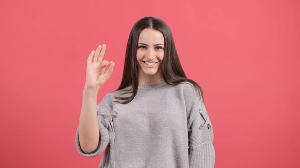 Happy Young Woman Showing Ok Sign with Fingers Isolated Over a Red Background