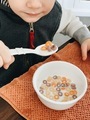 Young boy eating a spoonful of colorful cereal with milk from a white child-safe bowl - PhotoDune Item for Sale