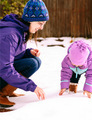 Mother and daughter in purple jackets and hats playing in the snow on a snow winter day  - PhotoDune Item for Sale