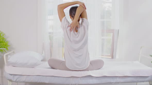 Calm of wellness Asian young woman sit on bed breathing and stretching before do yoga