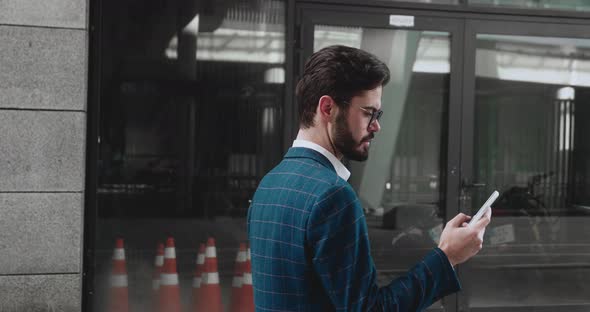 Serious Young Entrepreneur Browsing Mobile Phone Internet During Office Break Walking Along Business