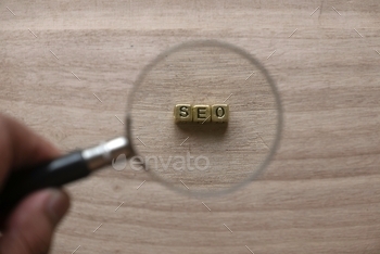 gnifying glass and look for gold alphabet beads of word SEO Search engine optimization on wooden background.internet, technology, data, design, information, optimization, flat, sign, web, background, analysis, digital, analytics, network, analyzing, magnify, lens, strategy, zoom, computer, social, development, website, management, report, page, chart, engine, magnification, isolated, look, document, discovery, exploration, review, find, analyze, focus, loo