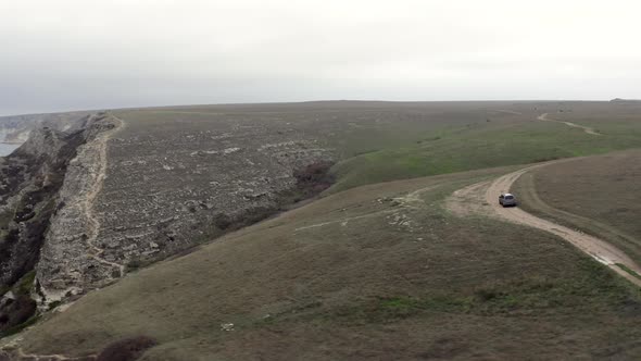 Gray Suv Car Drives Along Road Above White Rocky Cliffs