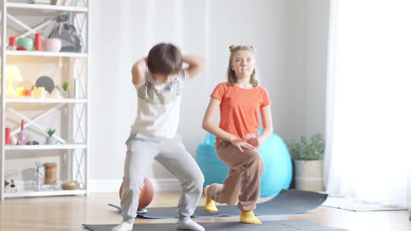 Wide Shot of Positive Active Caucasian Children Exercising at Home Indoors