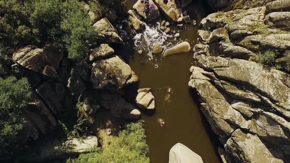 Friends Swimming in River Near Small Waterfall with Husky Dog Playing Frisbie