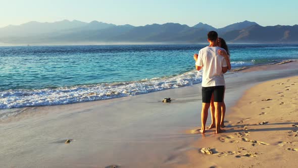 Young couple relax on tropical island beach time by blue sea and bright sand background of Gili Traw