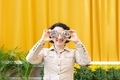 young woman holding two donuts in front of her eyes while walking down the street and smiling - PhotoDune Item for Sale