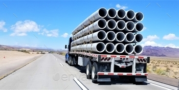  hauling a flat bed trailer filled with large PVC pipe for commercial construction use, under a beautiful sky of blue.