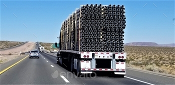 auling a flat bed trailer filled with construction pipes.