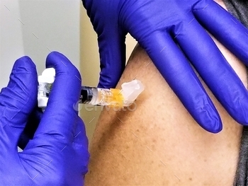 rse is injecting the flu shot immunization injection into the arm of the patient.