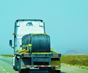  hauling a flat bed trailer filled with large spools of wire for commercial use.