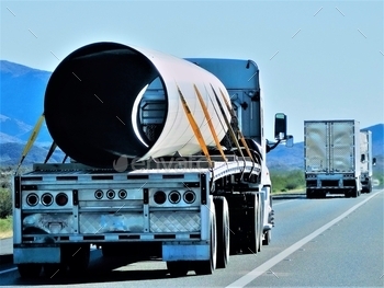  are seen hauling loads on the highway, including a very long, very big pipe on a flat bed trailer.