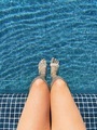 Woman dipping her legs in the outdoor swimming pool on a sunny summer day - PhotoDune Item for Sale