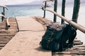 Backpack bags put down on coastline wooden bridge over blue natural seashore - PhotoDune Item for Sale