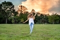 Little girl having fun on a grass in a city park at sunset - PhotoDune Item for Sale