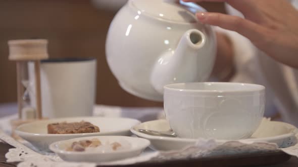 A woman pouring tea in a hotel room at a ski resort