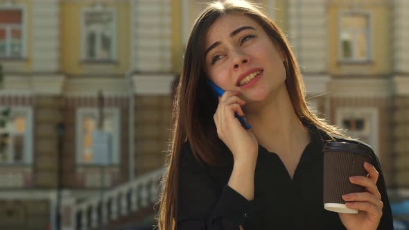 Girl Talks on the Phone on the Street of the City