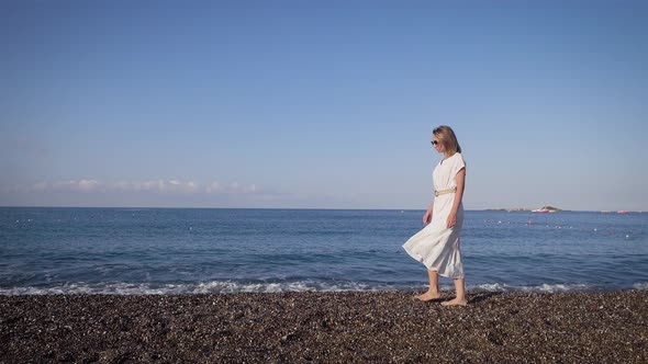 Slender Young Woman Against the Background of the Mediterranean Sea. Walk on a Summer Day Along the