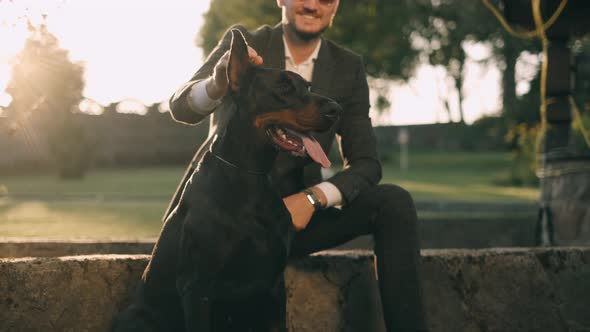 A Rich Businessman in a Business Suit Walks with a Big Doberman in the Park. A Successful Bearded