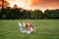 Little girl having fun on a grass in a city park at sunset - PhotoDune Item for Sale
