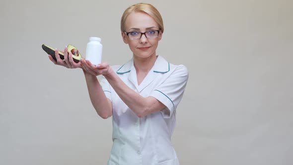 Nutritionist Doctor Holding Organic Avocado Fruit and Jar of Medicine or Vitamin or Omega 3 Capsules