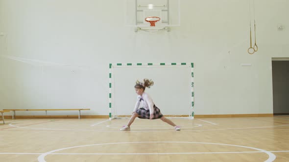Little Girl Sits on the Twine in the School Gym. Girl Performs Gymnastic Twine in the Gym.