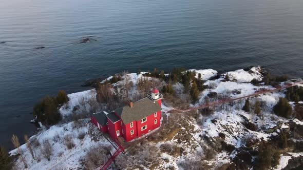 Red Lighthouse located in Marquette, Michigan in winter with rotating drone shot.