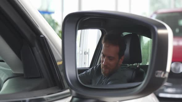 Selective Focua on a Side Mirror of a Car, Happy Man Relaxing in a New Auto