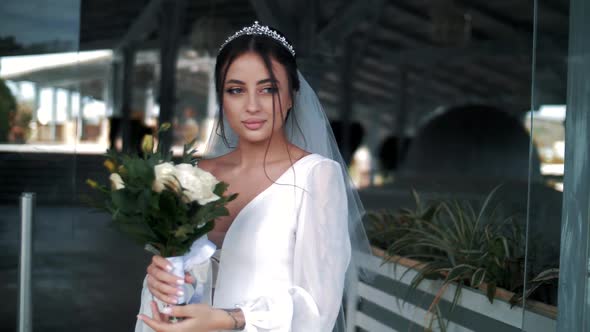 Incredibly beautiful young bride in a dress with a bouquet of roses