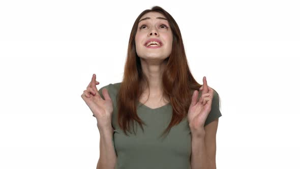 Portrait of Dreaming Woman in Casual Wear Keeping Fingers Crossed and Praying for Luck Isolated Over