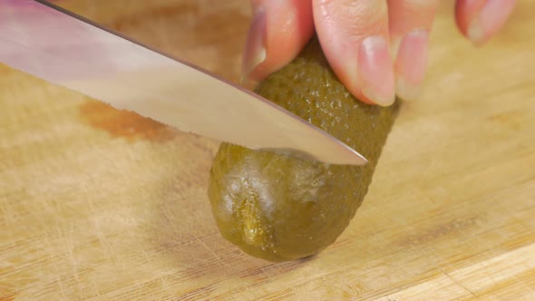 Pickled cucumber cutting piece with knife on wooden board 4K 2160p UHD footage - Gherkin piece on wo