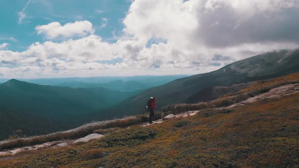 Aerial View of a Traveler with Backpack Climbing Along Mountain Slope. Epic Shot