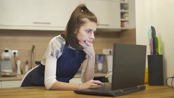 Young Beautiful Woman Looking for Recipes for Cooking on the Internet at Home 