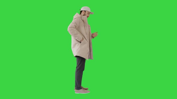 Man in Winter Clothes Using Sanitizer Spray To Prevent Flu Disease on a Green Screen, Chroma Key.