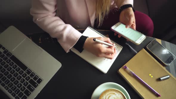 Close Up Caucasian Woman Hand on Wooden Table Inside Cafe Makes Notes in Notebook. Subject