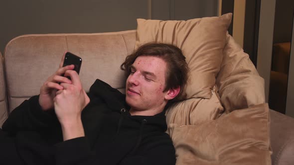 Portrait of Smiling Young Man Lying on Couch at Home