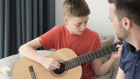 A Teenage Boy Playing Guitar at Home in a Family Circle