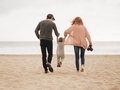 A young couple swings their young son on a cool morning on a sandy beach.  - PhotoDune Item for Sale