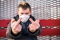 A man in a medical mask shows a middle finger indecent gesture in protest of quarantine  - PhotoDune Item for Sale