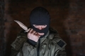 Tired bandit in balaclava and holding a knife on a brick wall background - PhotoDune Item for Sale