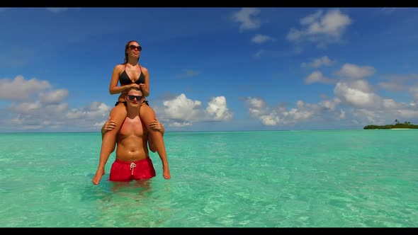 Two lovers sunbathing on perfect bay beach lifestyle by turquoise lagoon with clean sandy background