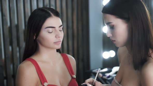 Woman Makeup Artist Applies Makeup To Cute Young Caucasian Model 