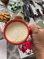 Overhead photo of hand holding a mug with coffee latte on the busy background with art supplies and  - PhotoDune Item for Sale