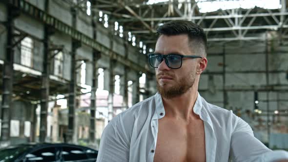 Bodybuilder with naked torso. Portrait of handsome muscular man in glasses