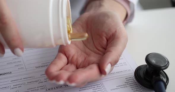 Person Pours Clear Yellow Omega 3 Capsules Onto Hand