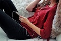 Girl in red sweater laying comfortably on the couch with her mobile phone and listening to the music - PhotoDune Item for Sale