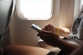 Young woman sitting in the airplane for a vacation and chatting with her friends on the phone.  - PhotoDune Item for Sale