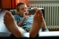 Teenage boy laying on the couch and using his phone. - PhotoDune Item for Sale